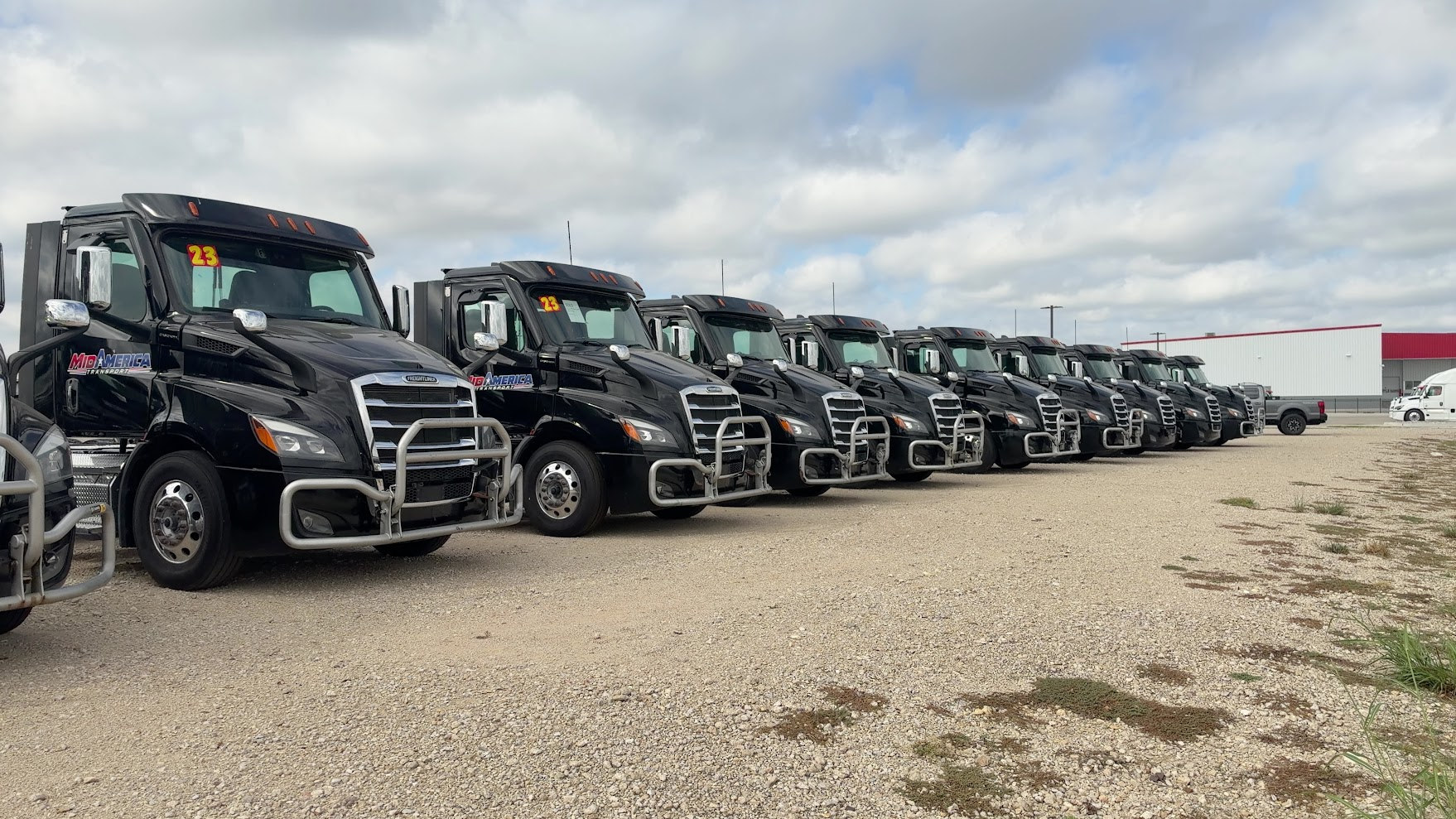 Actual MidAmerica Transport black tractors lined up in the staging lot